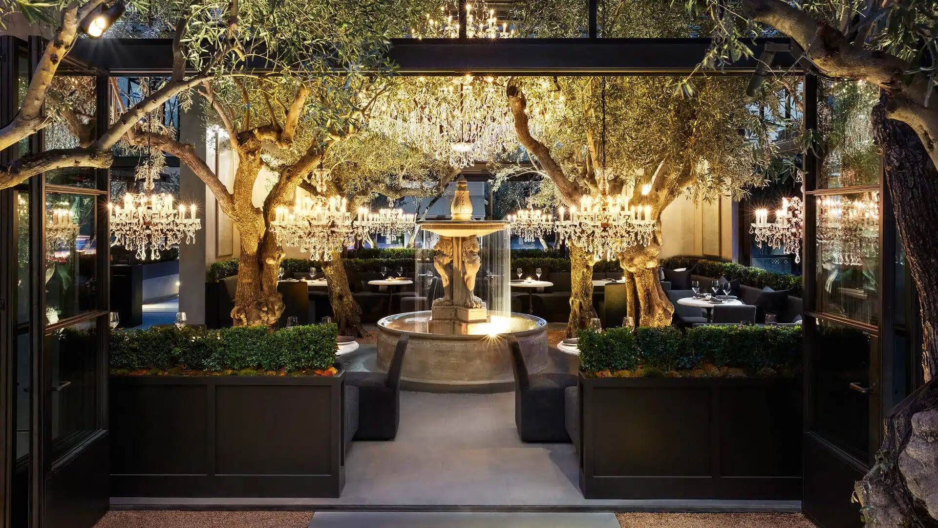 Restoration Hardware Restaurant in Yountville with chandeliers, olive trees, and a fountain centerpiece in courtyard dining.