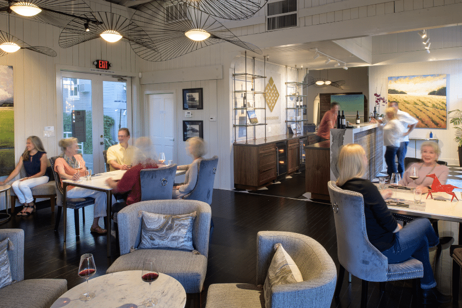 Tasting room with table and chairs and people enjoying wine tasting.