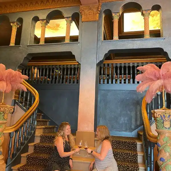 Two ladies with wine glasses on a grand staircase