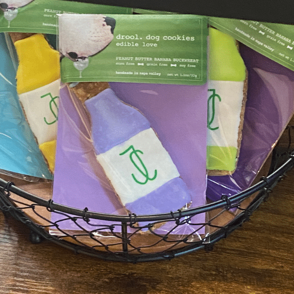 A basket of colorful gourmet dog cookies shaped like wine bottles with the Jessup Cellars logo