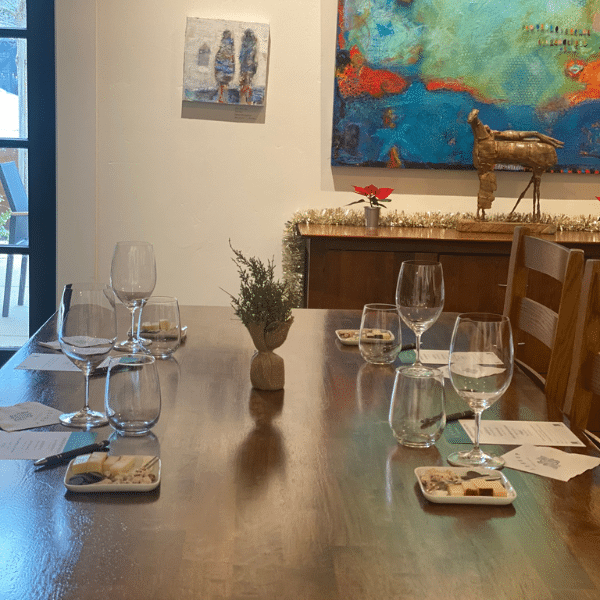 A wooden table set for 4 with wine glasses and small food pairing plates