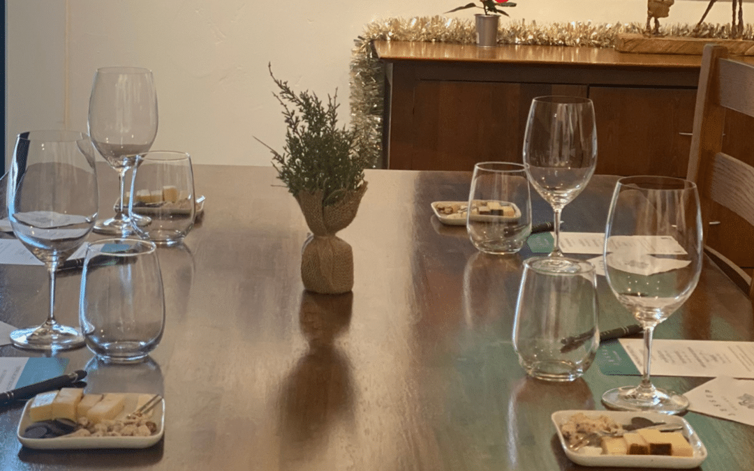 A wooden table set for 4 with wine glasses and small food pairing plates