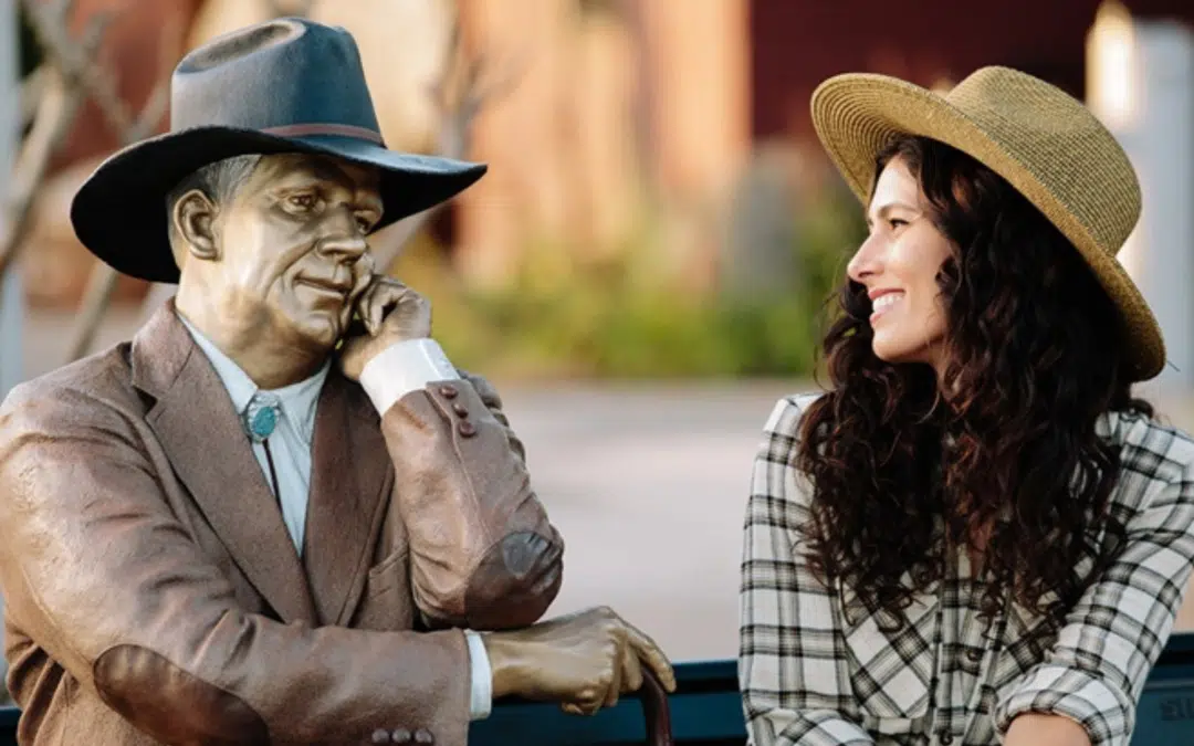 Woman smiles at bronze art piece title the sidewalk judge