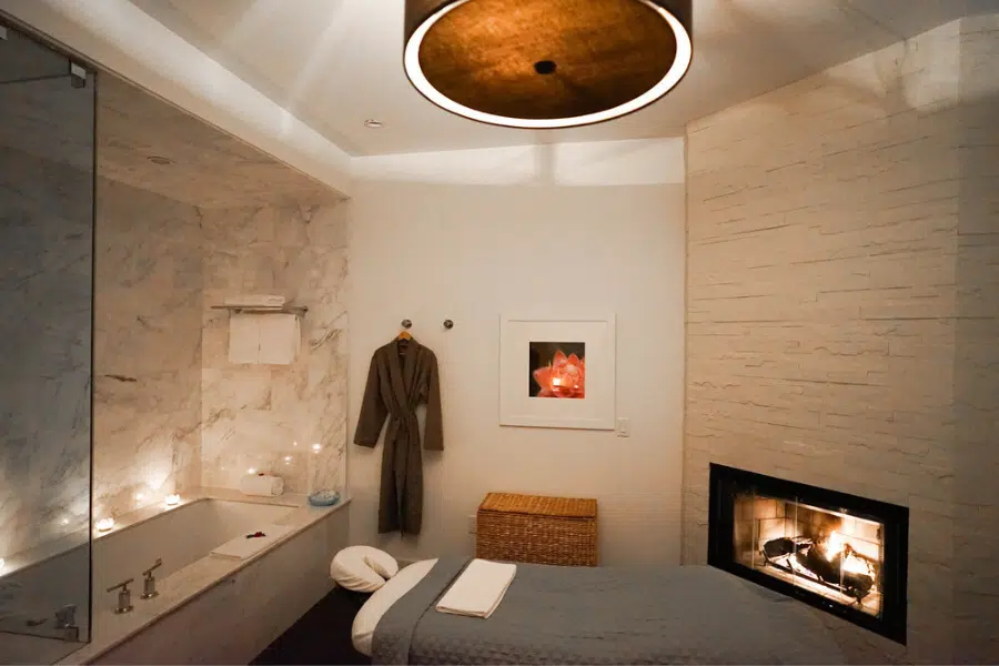 Treatment room featuring a fire place, massage bed, bathtub