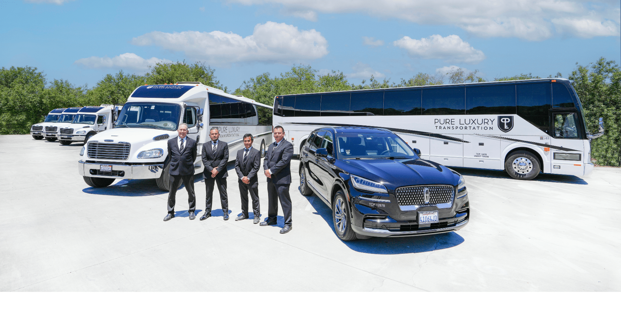 Men dressed in suits stand among several different vehicles including a bus, black sedan and a shuttle