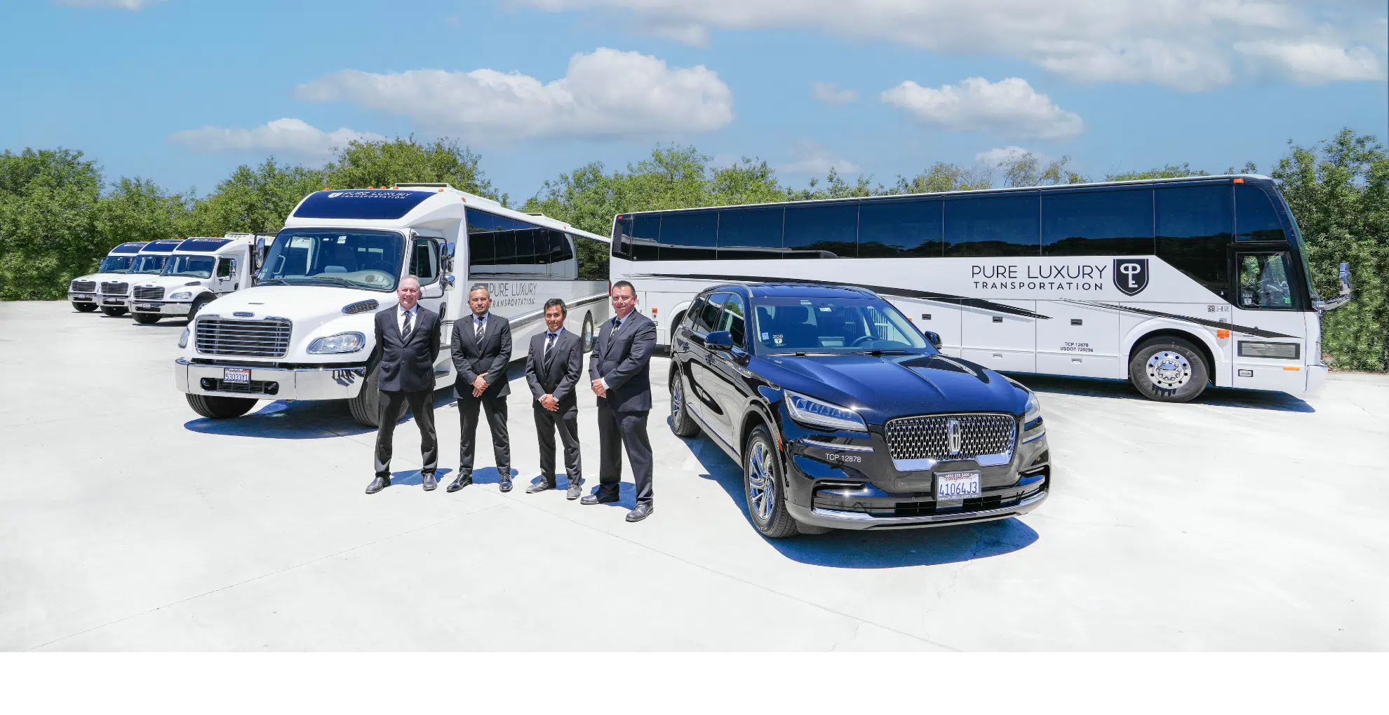 Men dressed in suits stand among several different vehicles including a bus, black sedan and a shuttle