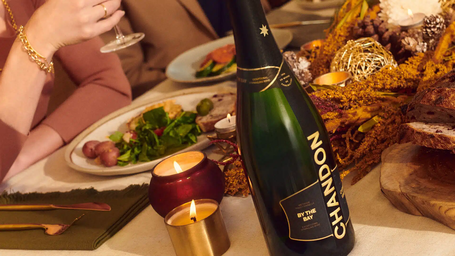 Chandon bottle of wine on table with a view of plates and hands holding glasses