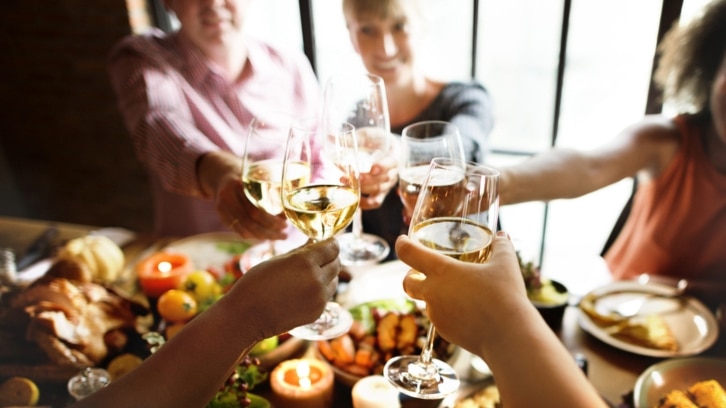 wine glasses being filled above table of food