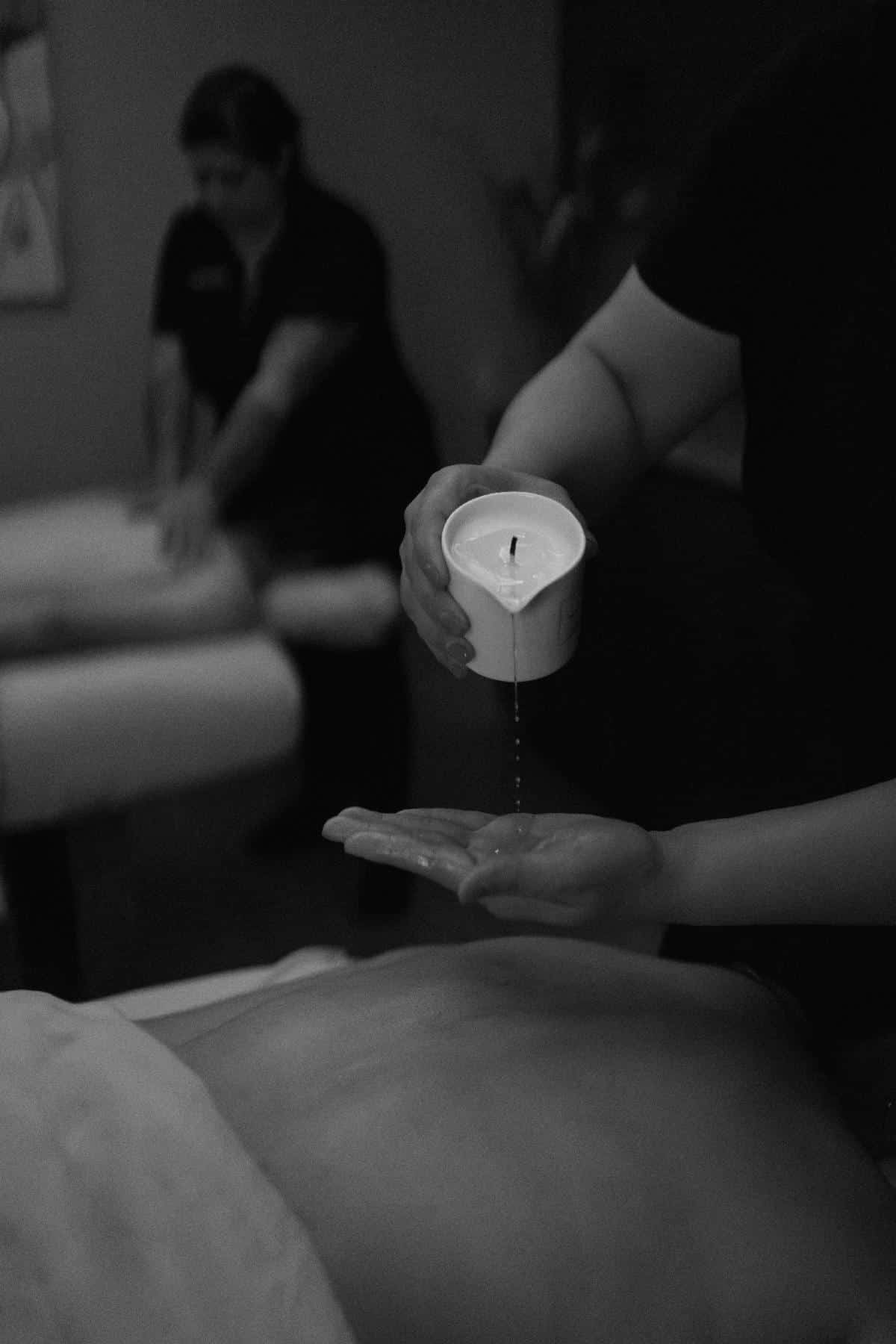 woman pouring candlewax on hand for spa experience