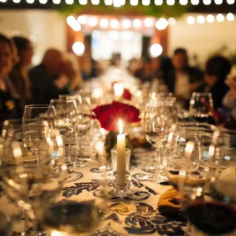 table set with candles and wine glasses surrounded by people