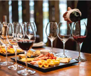 wine being poured into glasses with food on platters around