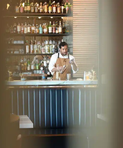 person behind bar pouring drink