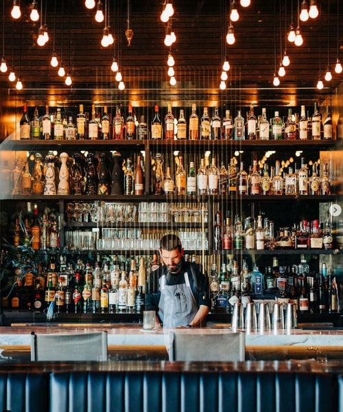 person behind bar pouring drink