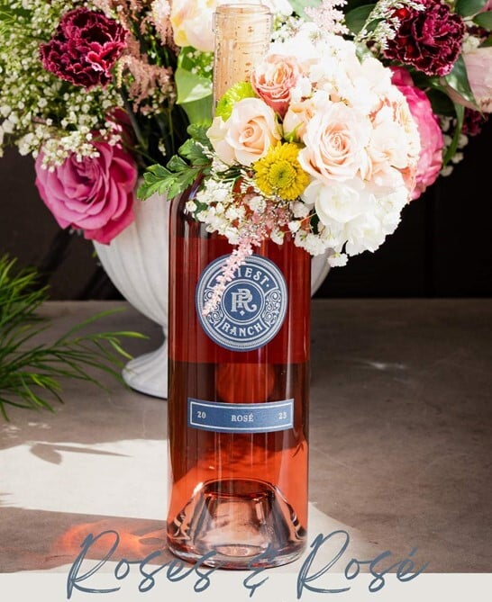 bottle of Rose surrounded by flowers