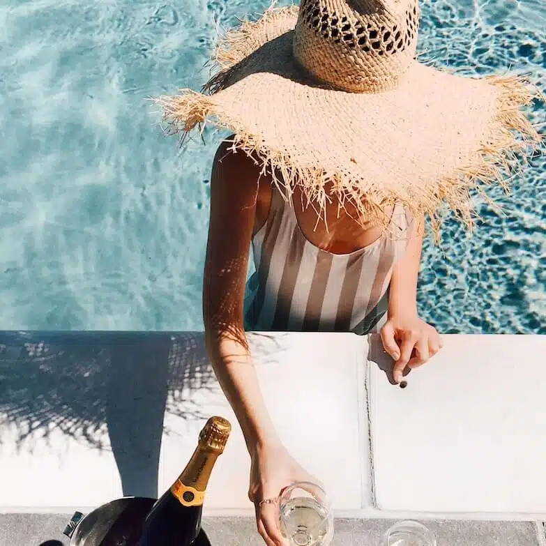 woman in pool with champagne drink