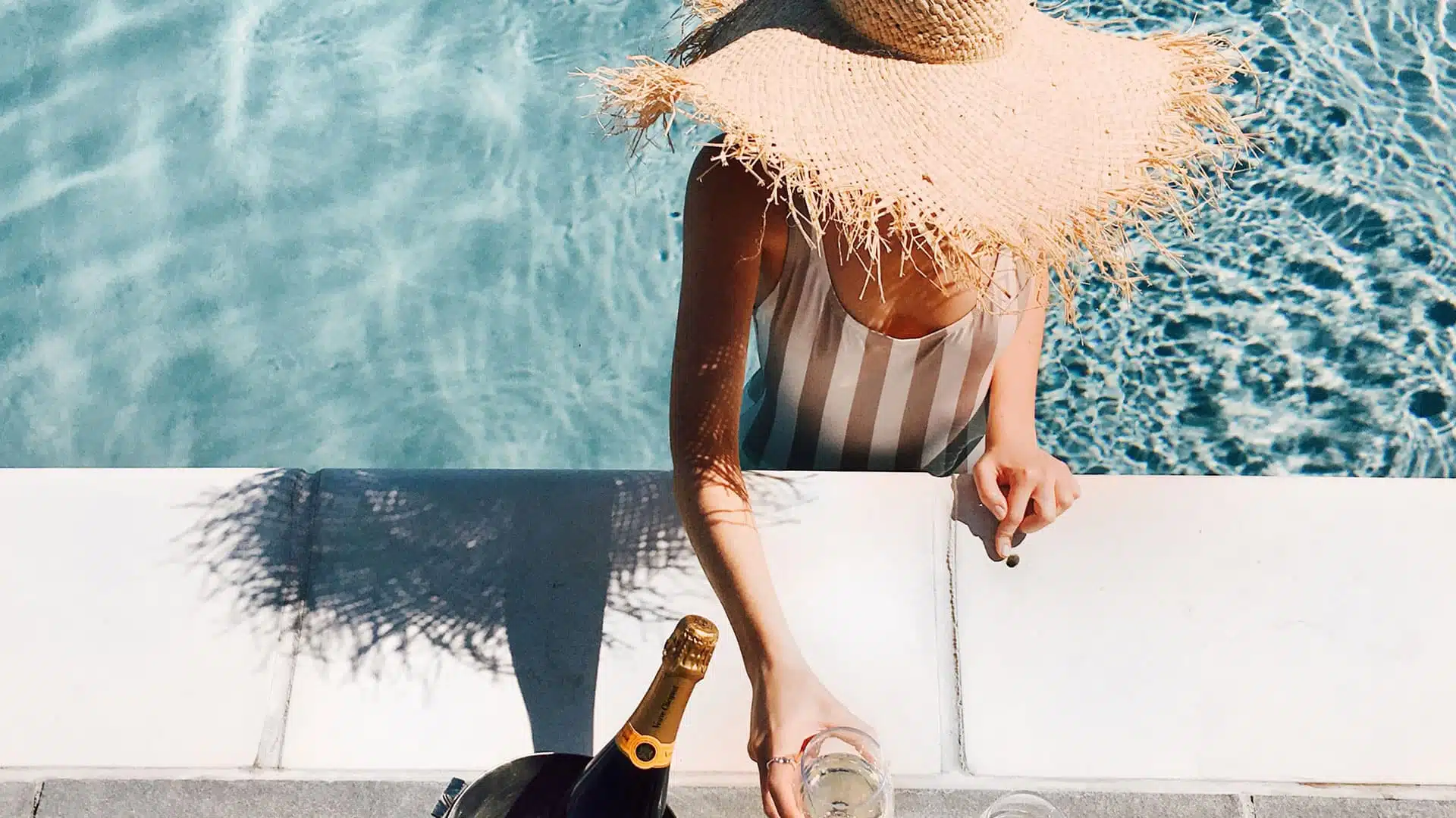 woman in pool with champagne drink