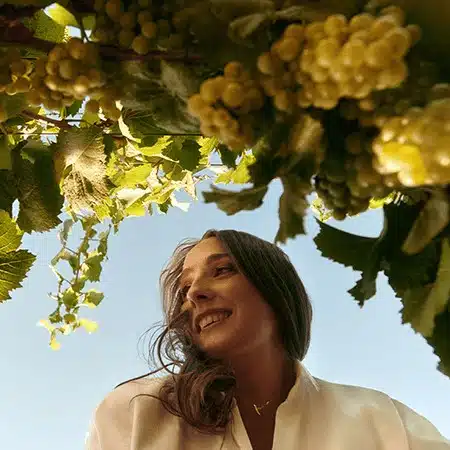 woman with her head around grapes on vine