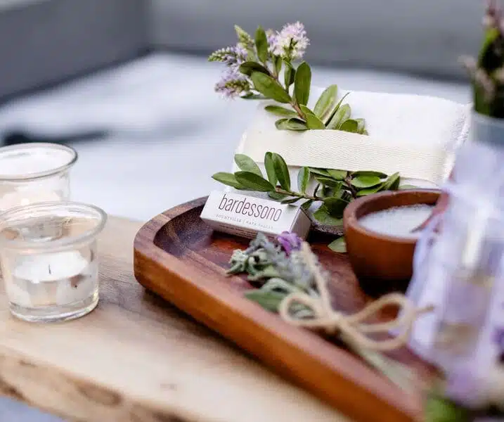 bath products on wooden board next to candles