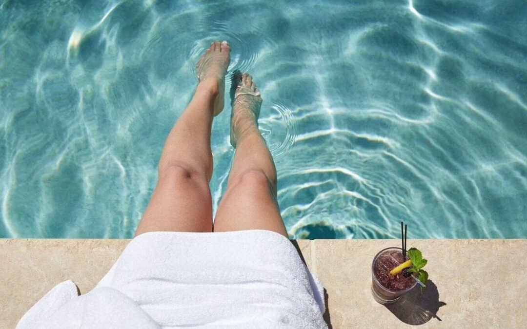 woman sitting next to a pool with a drink