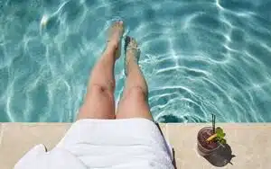 woman sitting next to a pool with a drink