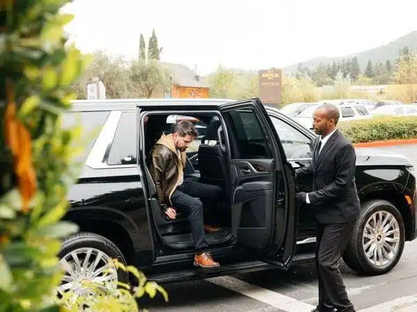 person getting out of car while someone holds door open