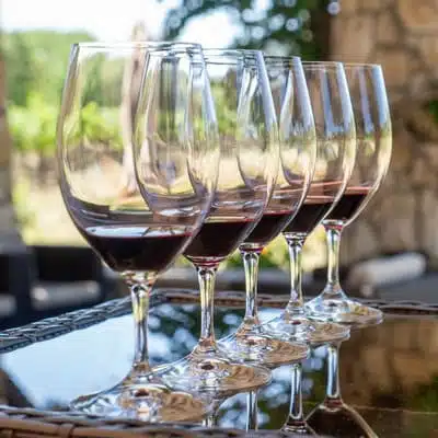 wine glasses lines up with red wine in them