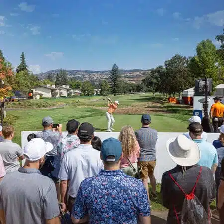 people standing around watching a guy swing a golf club