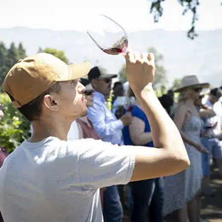 guy inspecting wine in wine glass outside<br />
