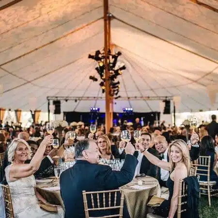 people sitting around tables under big tent