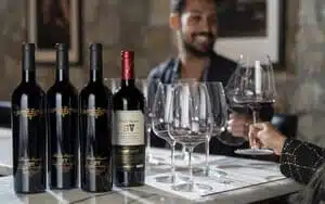 wine bottles on counter with person tasting wine behind